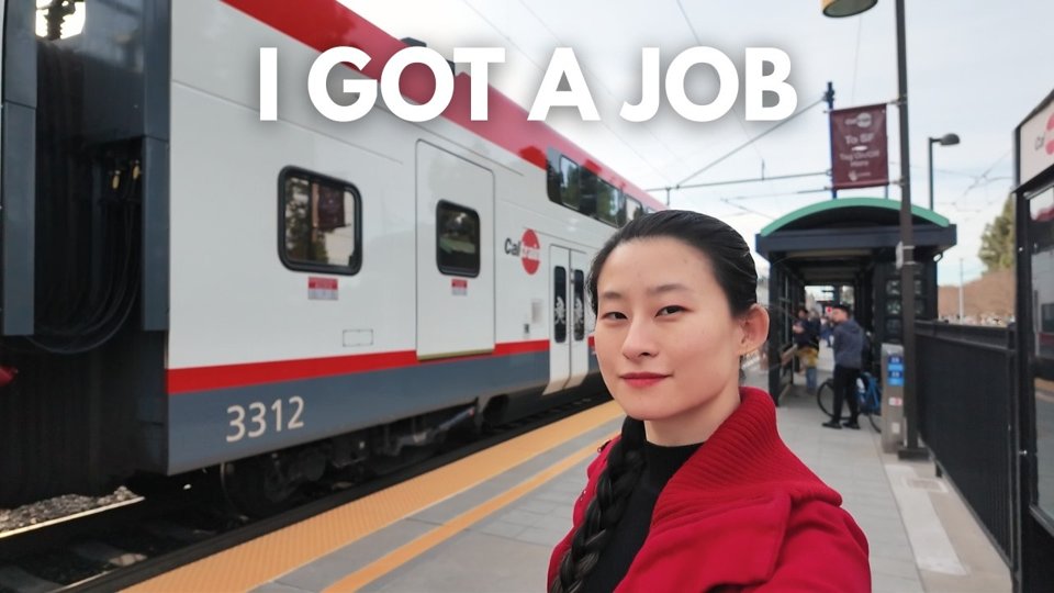 Yuqi in a red jacket on a Caltrain platform, captioned I got a job